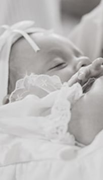 dítě v náručí během křtu