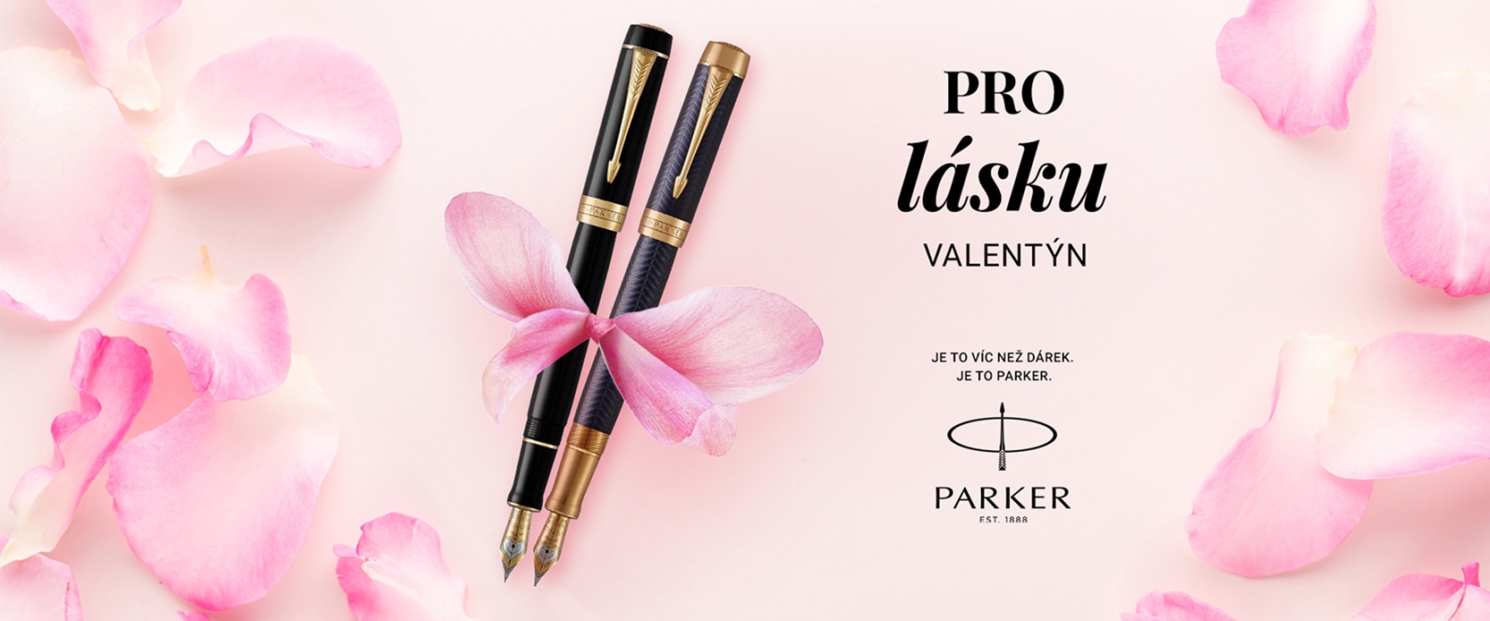 Dvě černé pera Parker svázané stuhou z růžových lístků na růžovém pozadí