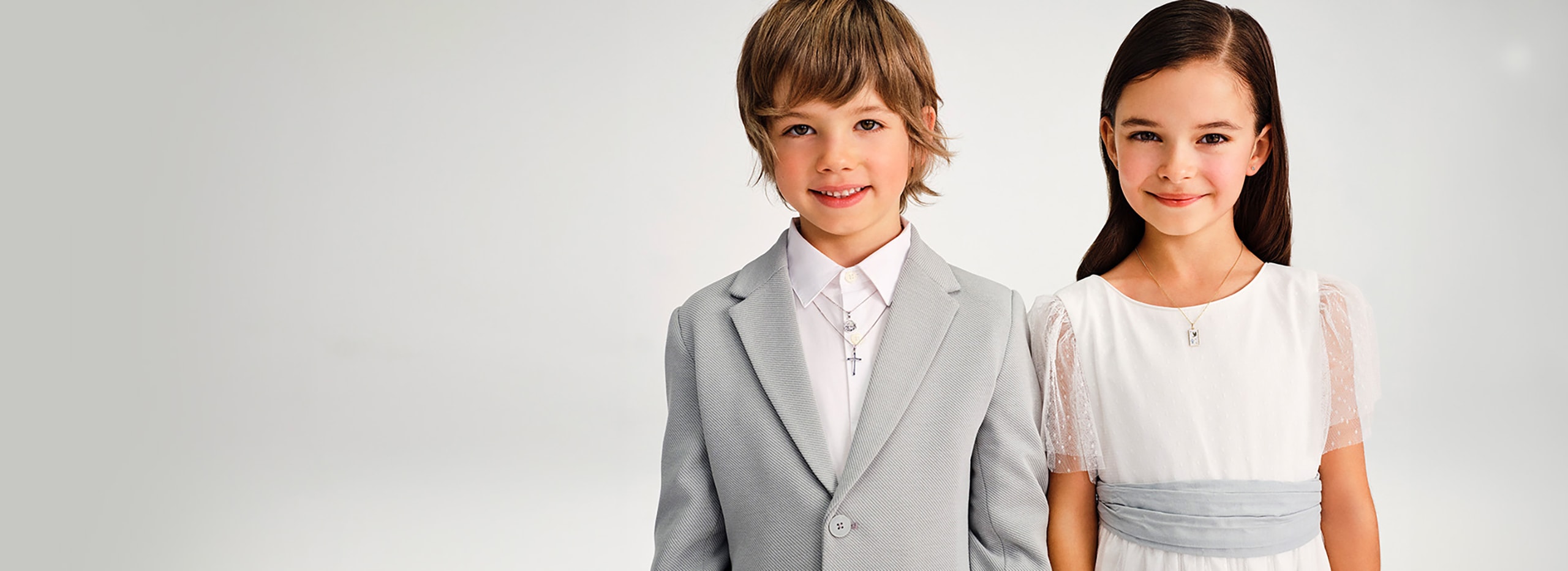 Chlapec a dívka oblečeni v lehkém oblečení, s přívěsky s motivem křtu