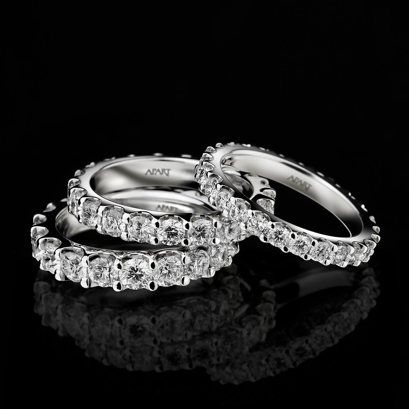 White gold diamond eternity rings with brilliant cut stones on a black reflective surface