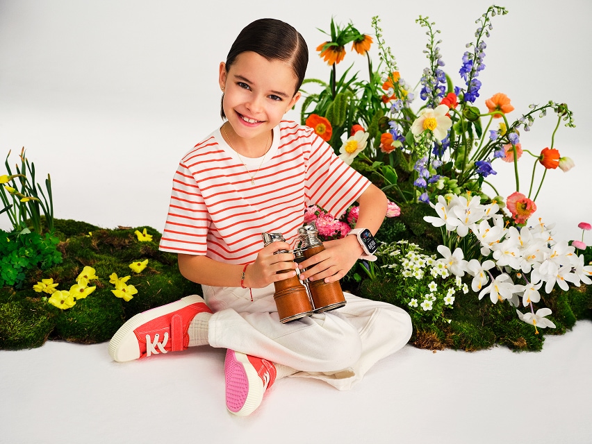 Kids Collection - a girl in a meadow with wildflowers in the background, presenting a watch and a bracelet
