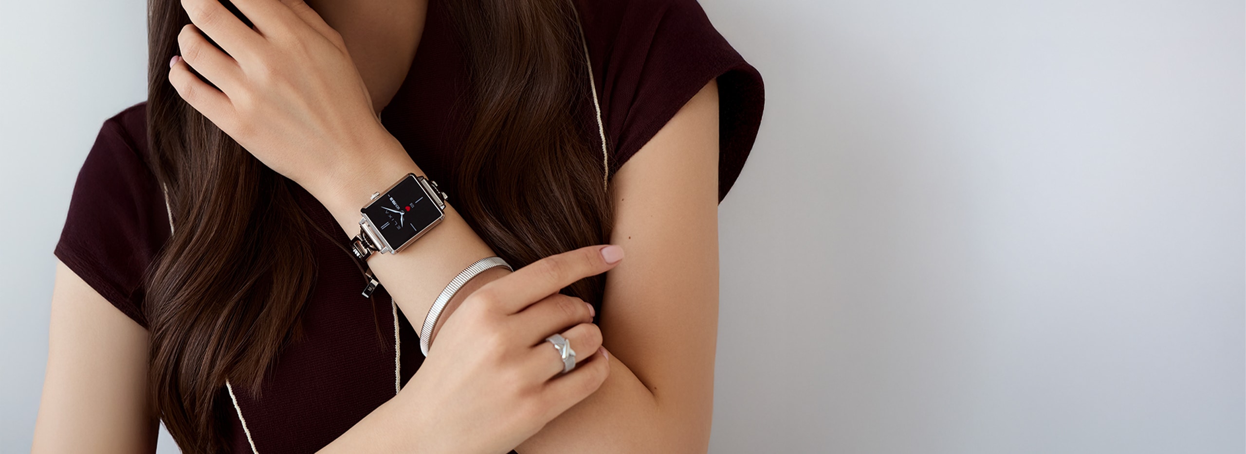 A woman showcasing an Elixa smartwatch with a steel case and bracelet