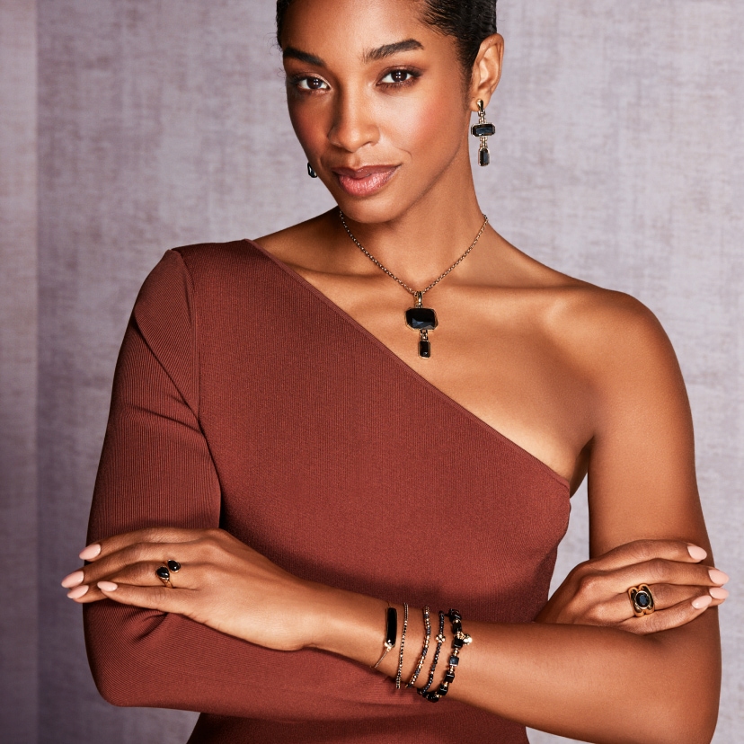 Yaritza Reyes-Zmysłowska w bordowej sukience prezentująca biżuterię z ciemnymi kamieniami 