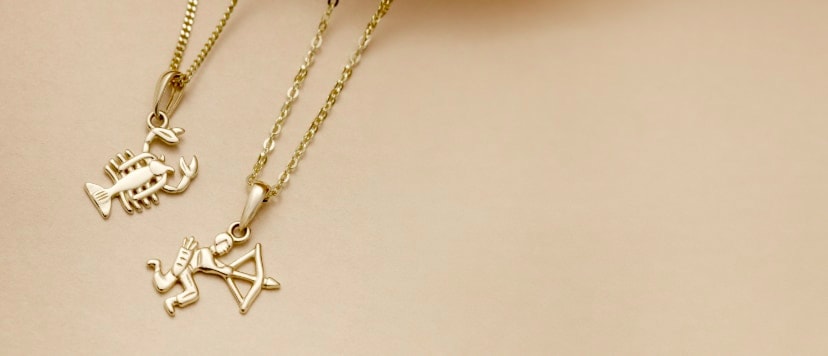 Dwie złote zawieszki z motywem znaku zodiaku: skorpion i strzelec