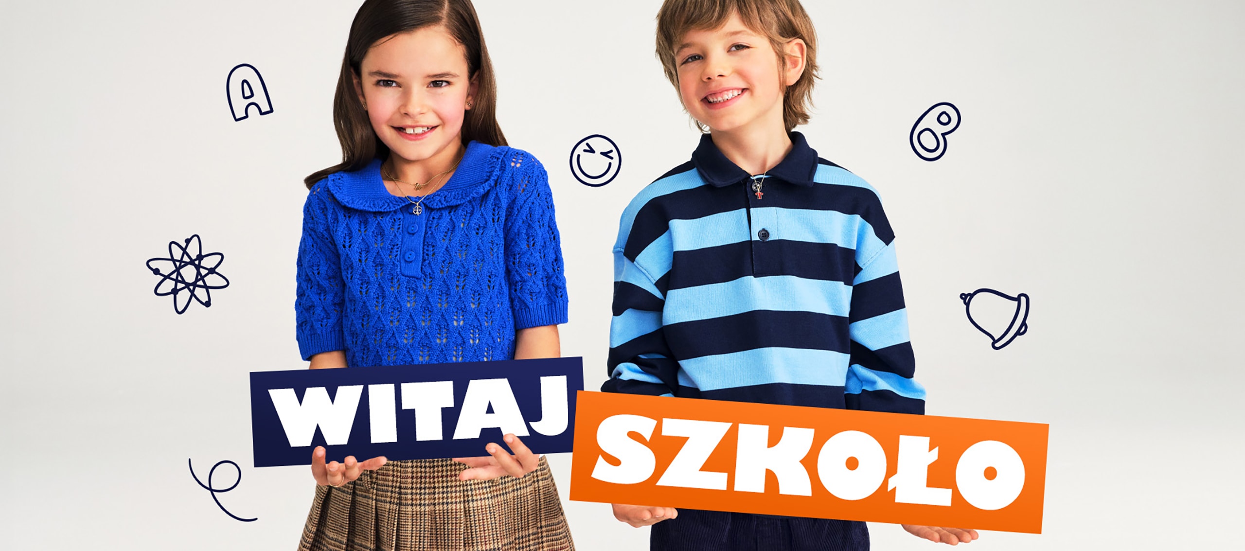 Dziweczynka i chłopiec trzymający w rękach napis witaj szkoło