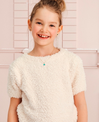 Dziewczynka w beżowej koszulce prezentująca zawieszki