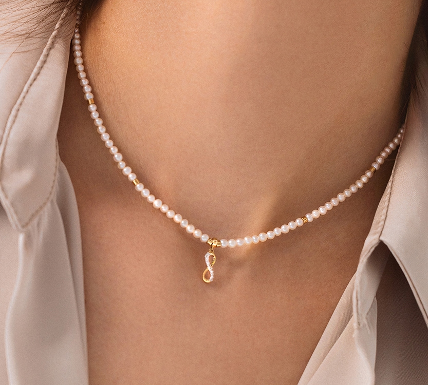 Perłowy naszyjnik ze złotą zawieszką w kształcie znaku nieskończoności