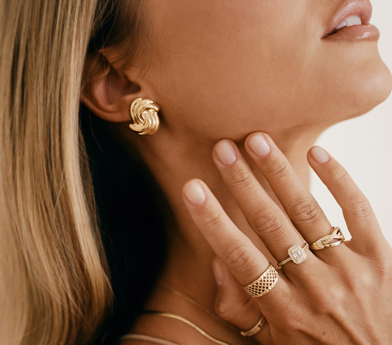 Modelka prezentuje złote kolczyki i pierścionki