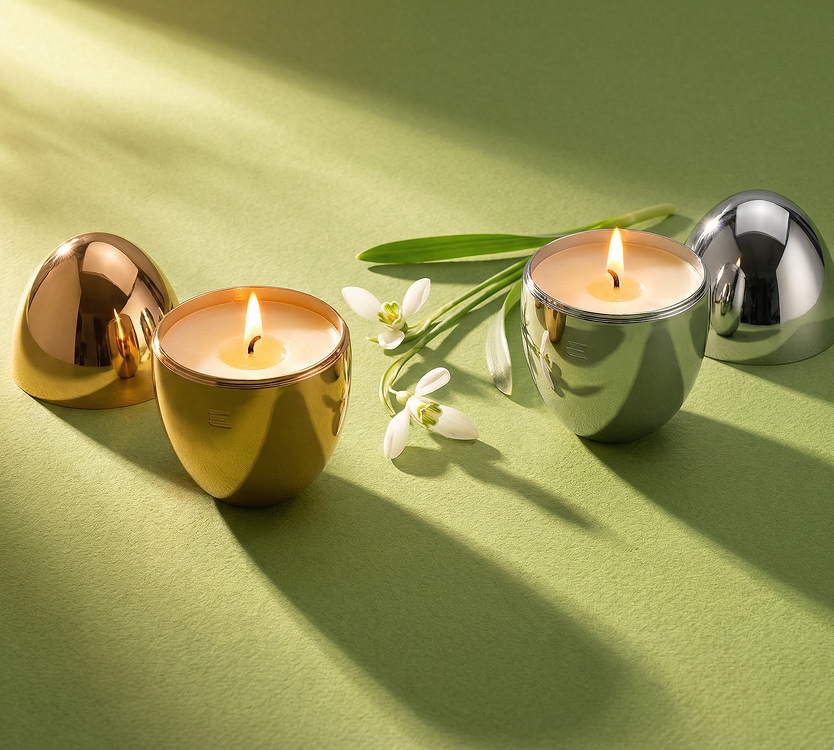 Palące się świece zapachowe, kwiaty przebiśniegi na zielonym tle