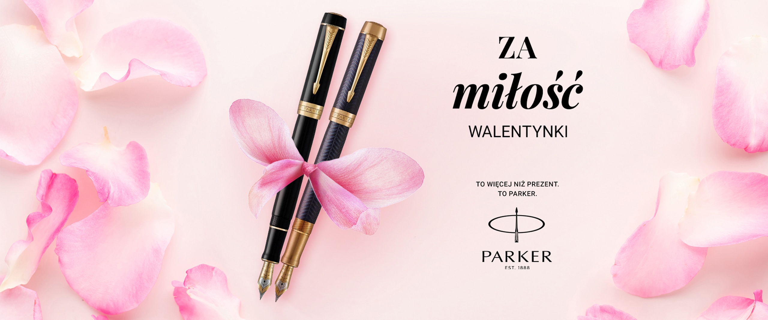 dwa czarne pióra marki Parker przewiązane wstążką z płatków róży na różowym tle