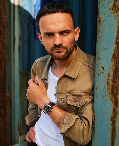 Bartosz Zmarzlik prezentuje naszyjnik oraz zegarek marki Aztorin