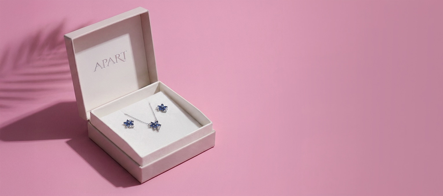 Różowe pudełko prezentowe z logiem apart, a w nim komplet srebrnej biżuterii