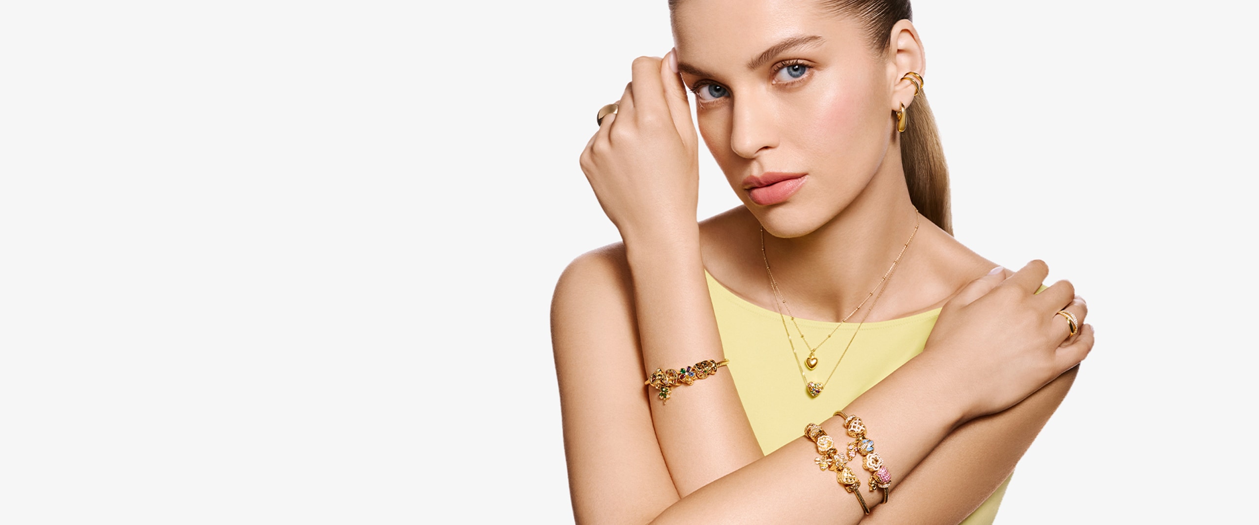 Modelka prezentująca złotą biżuterię oraz złote bransoletki beads