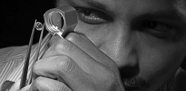 Mężczyzna ocenia diament przez szkło powiększające