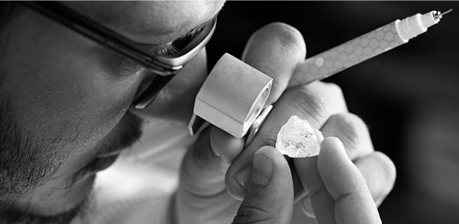 Mężczyzna ogląda nieoszlifowany diament przez szkło powiększające