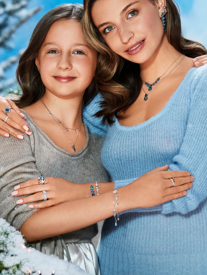 Julia Wieniawa z dziewczynką ubraną w szary sweter prezentują biżuterię