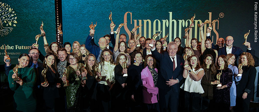 Grupa ludzi, mężczyzn i kobiet ze wzniesionymi w górę statuetkami Superbrands