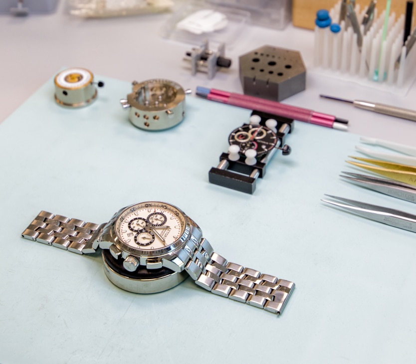 leżący na biurku zegarek marki Aztorin, obok przyrządy do naprawy zegarków