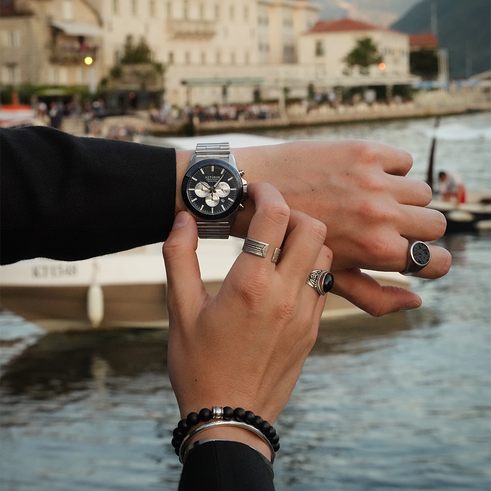 Mężczyzna prezentujący zegarek oraz dodatki męskiej biżuterii - sygnety i bransoletki