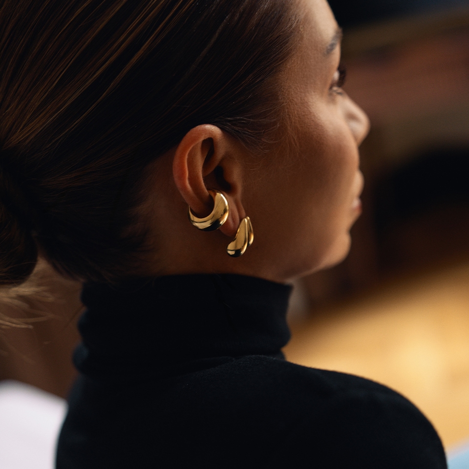 Kolczyki pozłacane o nieregularnych kształtach w motywie łezki zawieszone na uchu