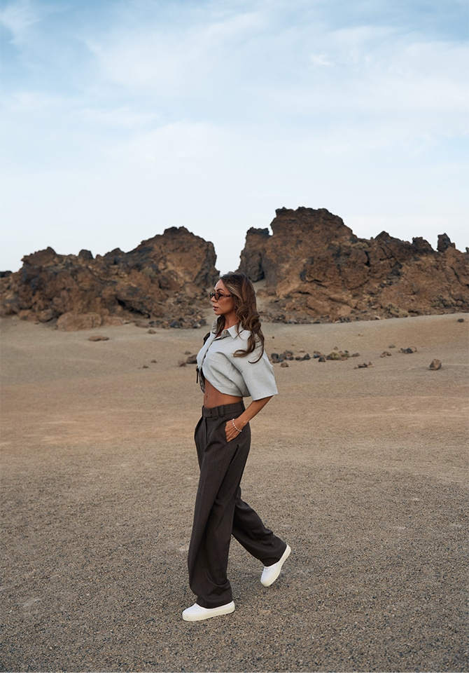 Kobieta na tle gor pustynnych w stylizacji letniej prezentująca komplet biżuterii złotej