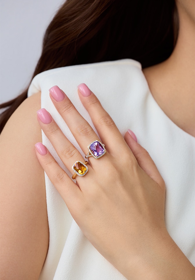 kobieta prezentująca na palcach u dłoni złote pierścionki z kamieniami szlachetnymi