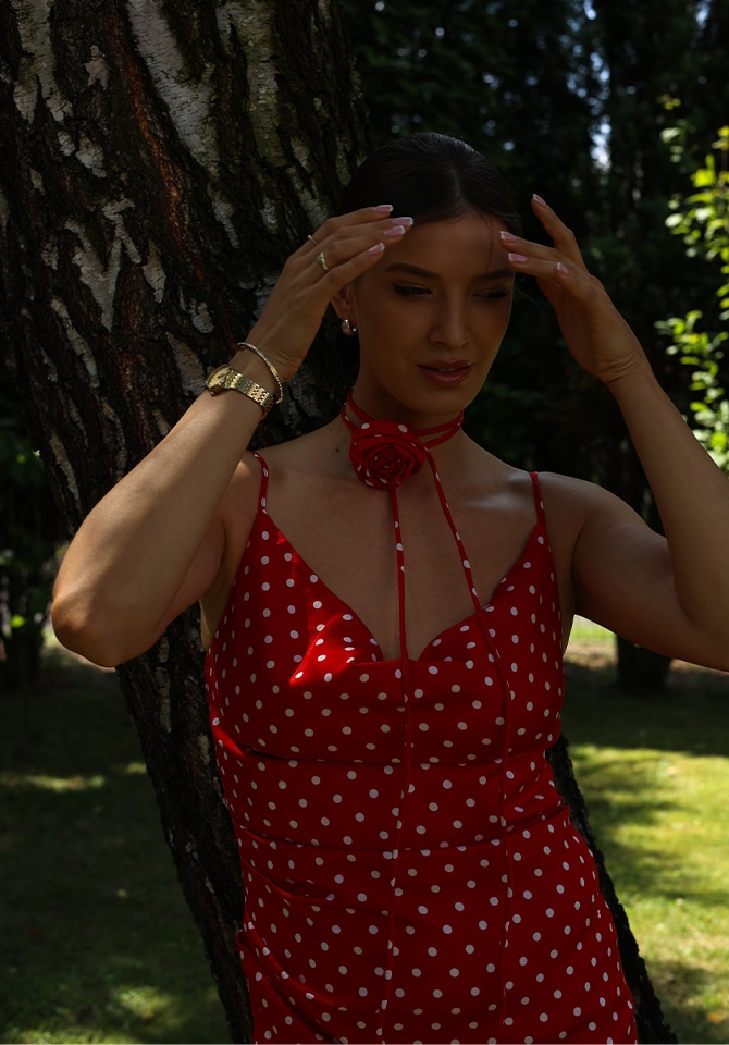 Kobieta w czerwonej letniej sukni z dodatkami złotej bizuterii