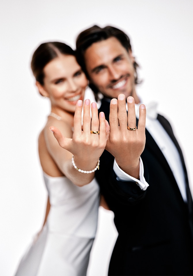 Uśmiechnięci mowożeńcy prezentują złote obrączki