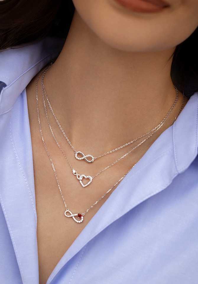 Naszyjniki srebrne z zawieszkami z cyrkoniami zawieszone na szyji