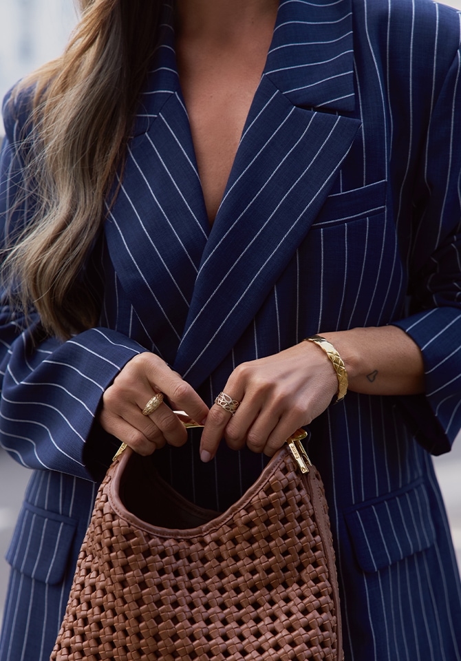 Kobieta w w długiej granatowej marynarce w białe paski w stylizacji pierścionkó złotych