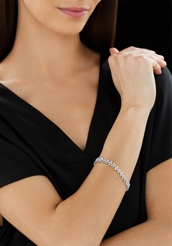 Kobieta prezentująca bransoletkę z białego złota w motywie kwiatowym