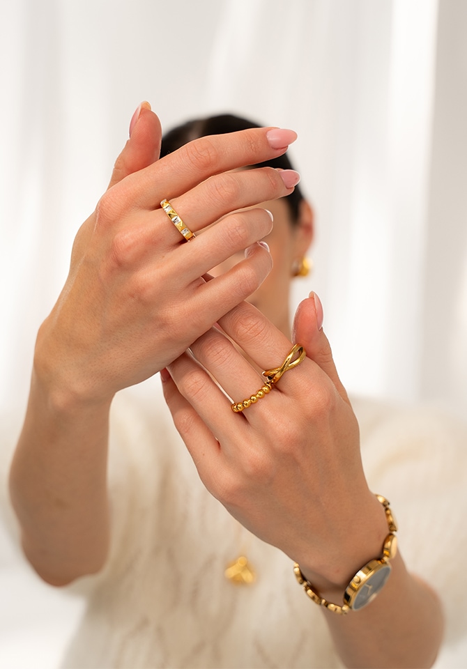 kobieta prezentująca na palcach u dłoni pierścionki pozłacane