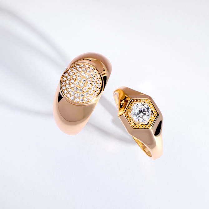 Dwa złote pierścionki z diamentami na szarym tle