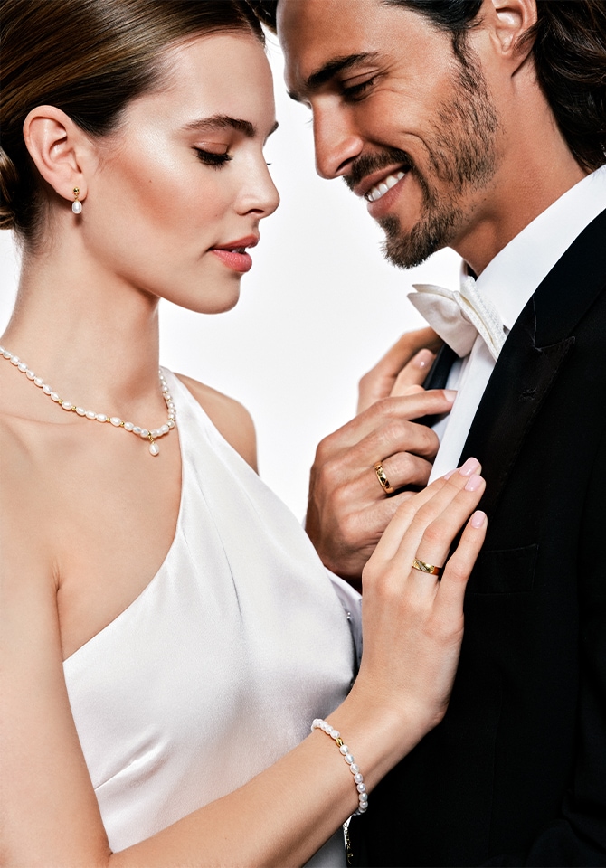 Para młoda skierowana twarzą do siebie prezentująca biżuterię ślubną w sesji zdjęciowej