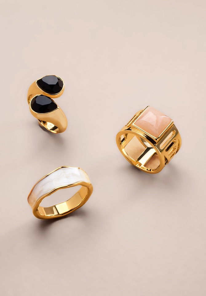 Grafika przedstawiajaca trzy pozłacane pierścionki obłożone masą perłową, kamieniem agat oraz kwarcem w kolorze pudrowego różu