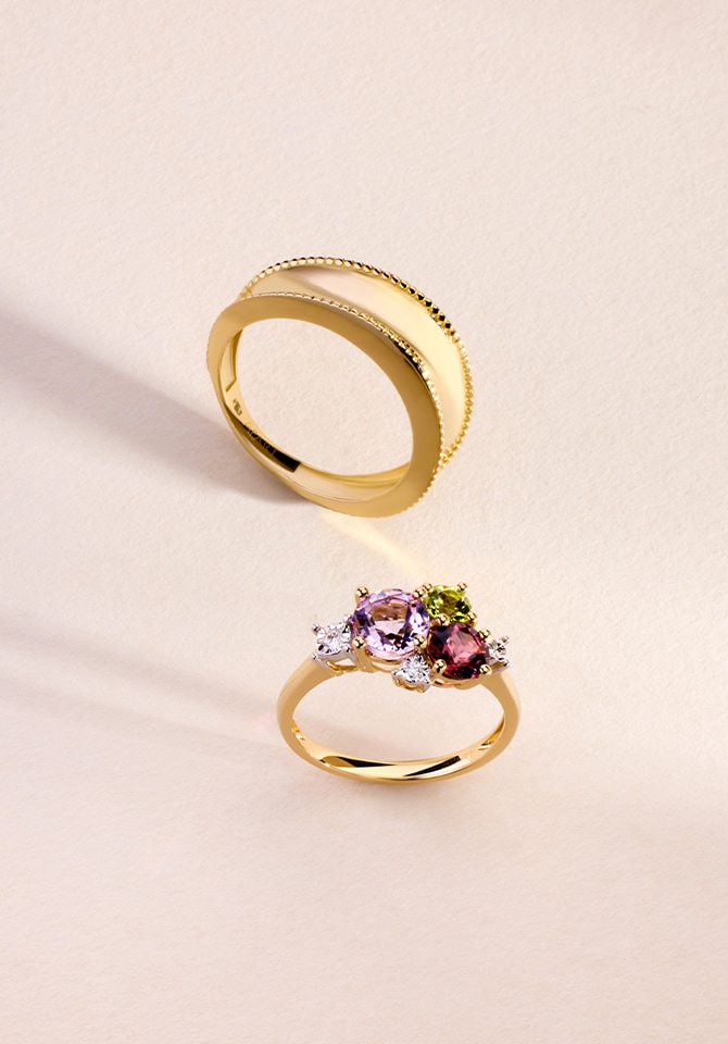 Grafika przedstawiająca dwa złote pierścionki jeden z nich dodatkowo obłożony jest kolorowymi cyrkoniami