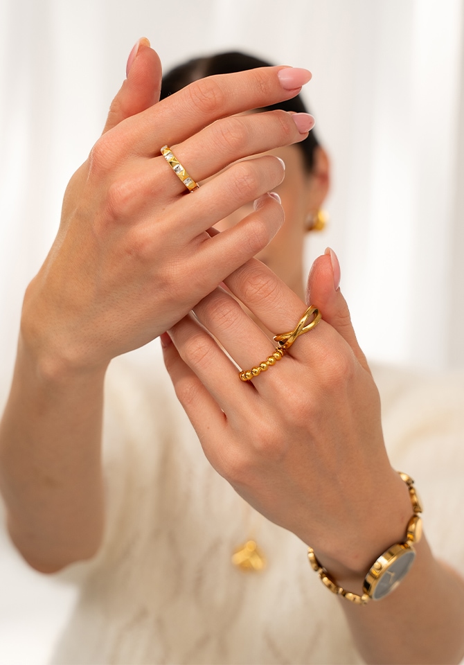 kobieta prezentująca na palcach u dłoni złote pierścionki