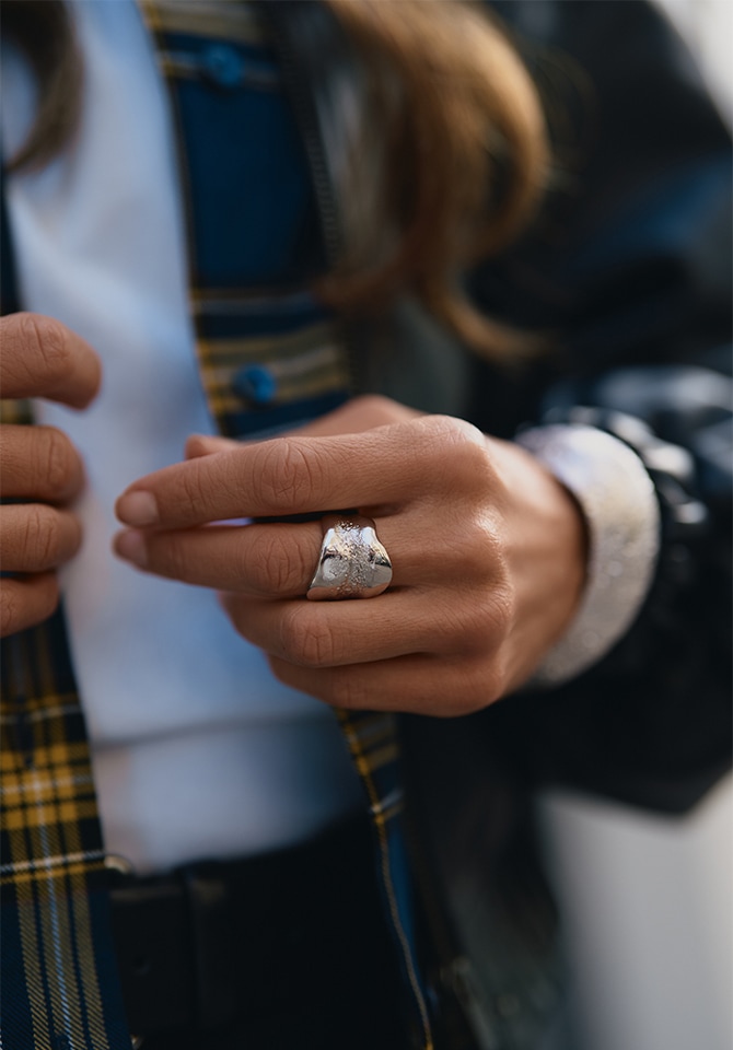 kobieta prezentująca na palcach u dłoni srebrny pierścionek oraz na nadgarstku bransoletkę srebrną