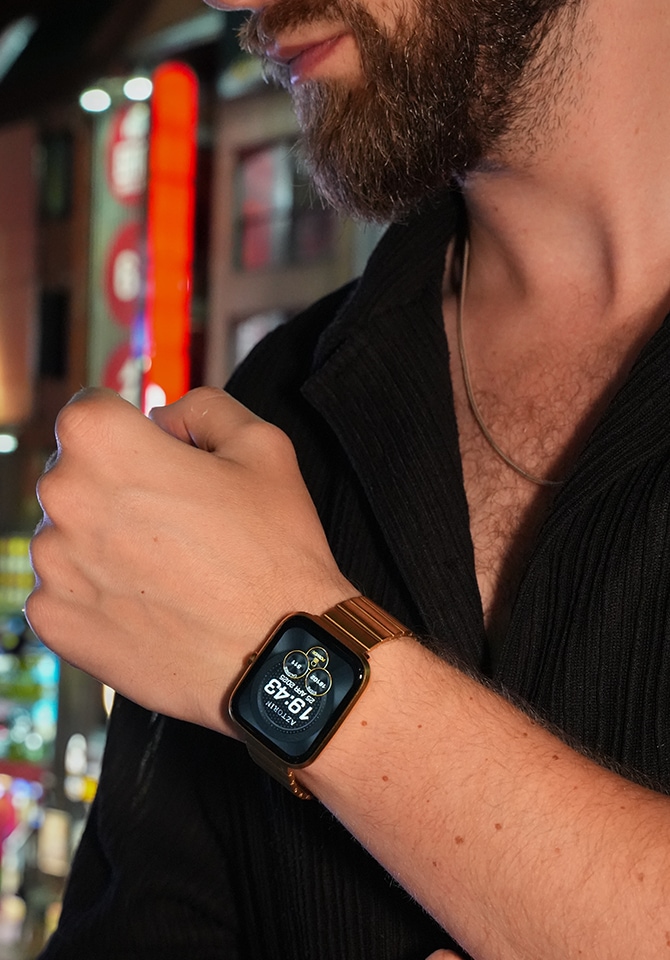 Mężczyzna ubrany w czarną koszulę prezentujący smartwatch z bransoletą z mosiądzu założony na nadgarstku