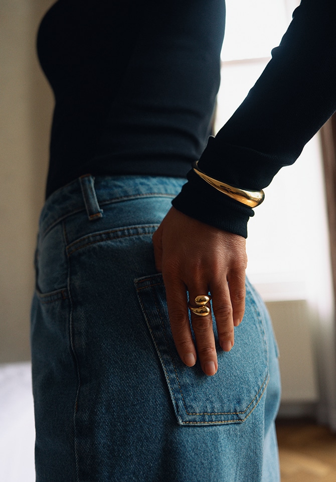 kobieta prezentująca komplet złotej biżuterii - pierścionek i bransoletkę