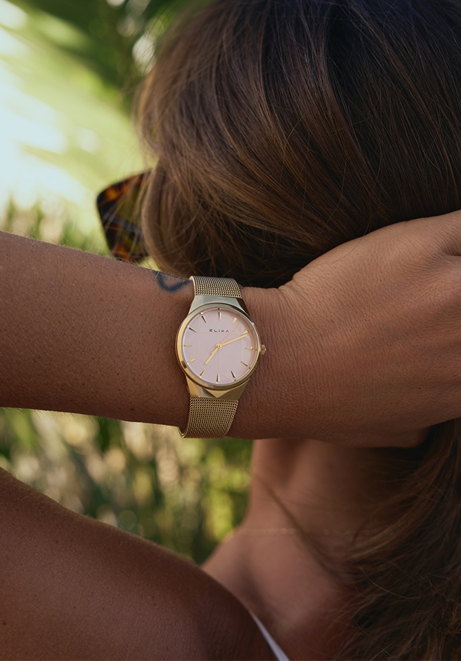 zegarek z bransoletą z mosiądzu oraz białą tarczą założone na nadgarstku kobiety