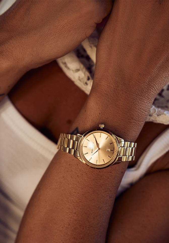zegarek ze złotą tarczą i bransoletą z mosiądzu założony na nadgarstku