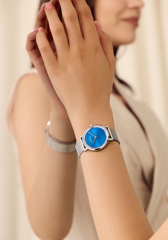 zegarek damski z bransoletą ze stali szlachetnej oraz niebieską tarczą założony na nadgarstku
