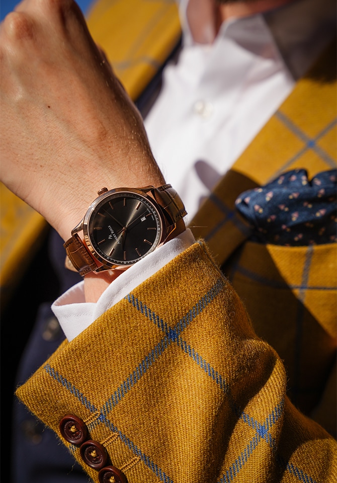 Mężczyzna prezentujący na nadgarstku zegarek z bransoletą ze skóry wkolorze ciemnego brązu