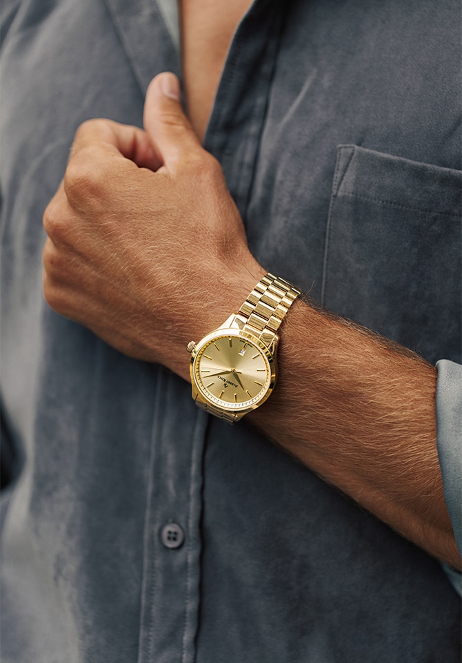 Mężczyzna prezentujący na nadgarstku zegarek z bransoletą ze stali szlachetnej w kolorze złota
