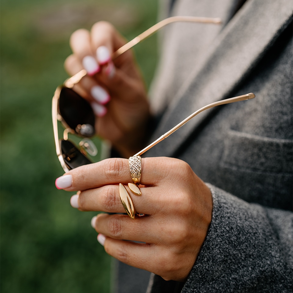 Dwa złote pierścionki w tym jeden z diamentami założone na palcach kobiety