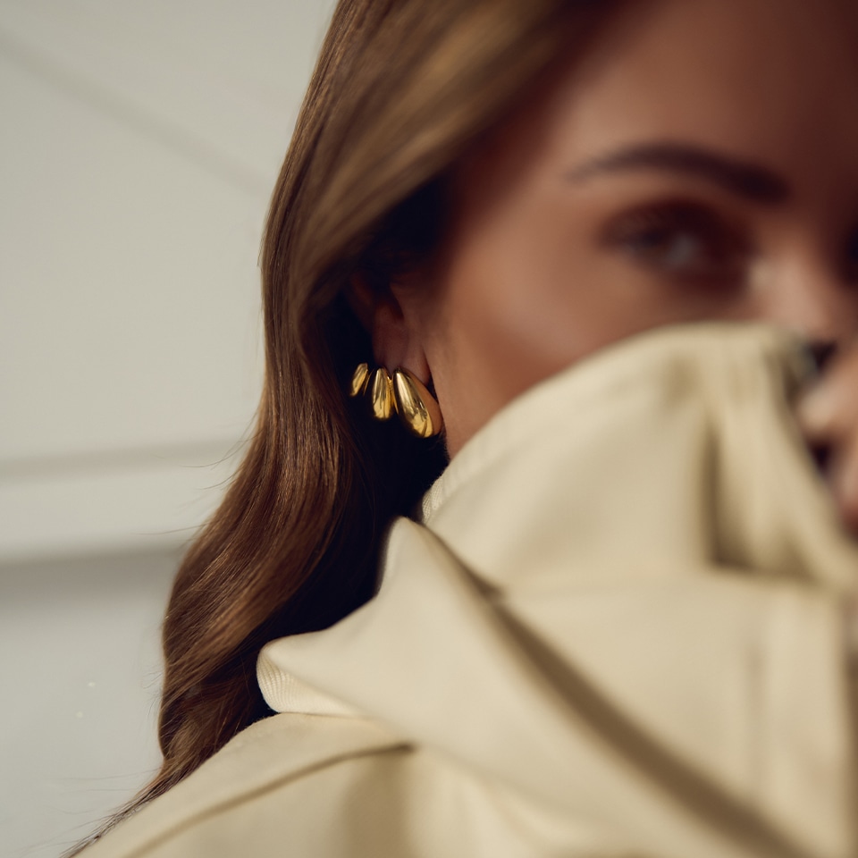 Kobieta prezentująca kolczyki pozłacane w kształcie łezki
