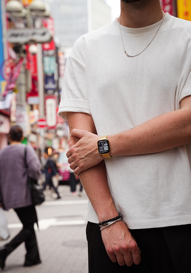 Mężczyzna prezentujący zegarek i bransoletkę męską na tle tłumu ludzi 