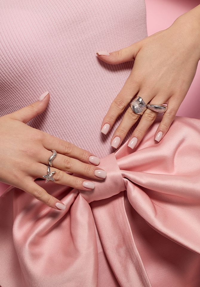 Kilka srebrnych pierścionków prezentowanych na palcach kobiety