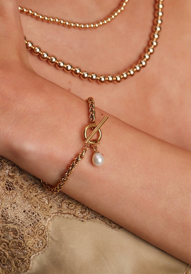 Bransoletka z zawieszką z perłą założona na nadgarstku kobiety